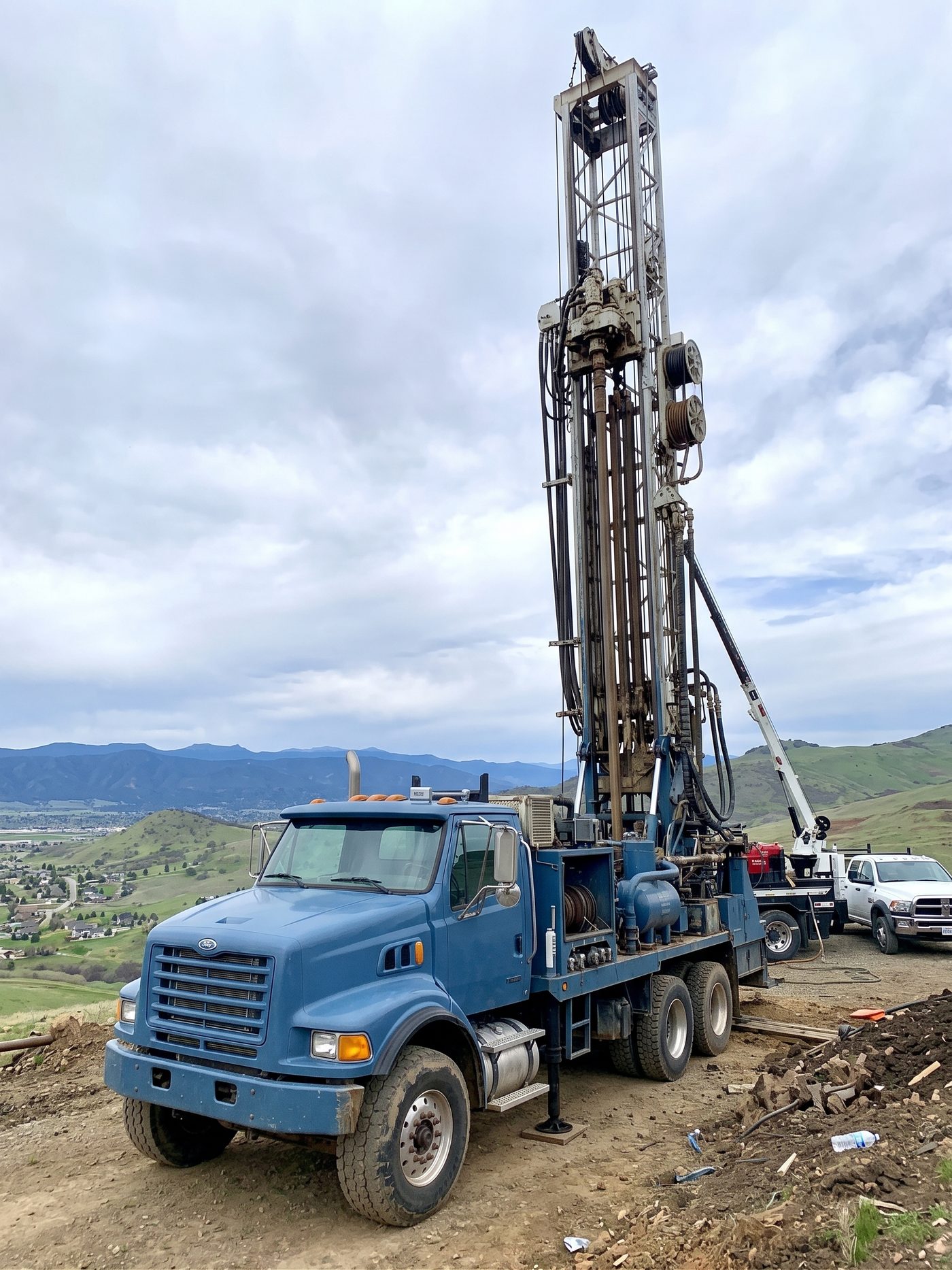 Water well drilling rig set up on a hillside property